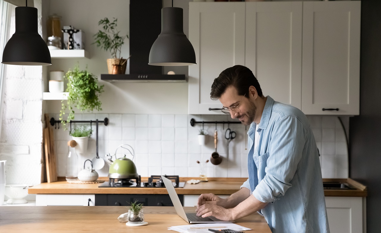 Person working on laptop on kitchen counter banner