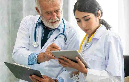 Deux médecins en blouse de laboratoire discutent des rapports des patients sur leurs tablettes