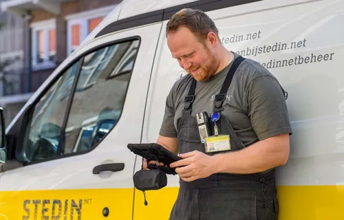 mobile network engineer looking at tablet in front of his van