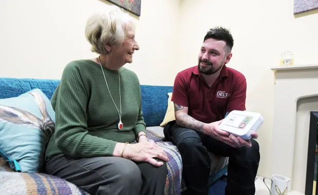 Delta Wellbeing worker talks to elderly care patient on sofa