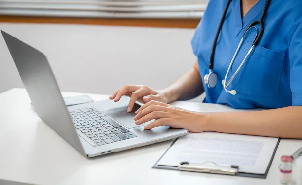 medical professional typing on a computer 