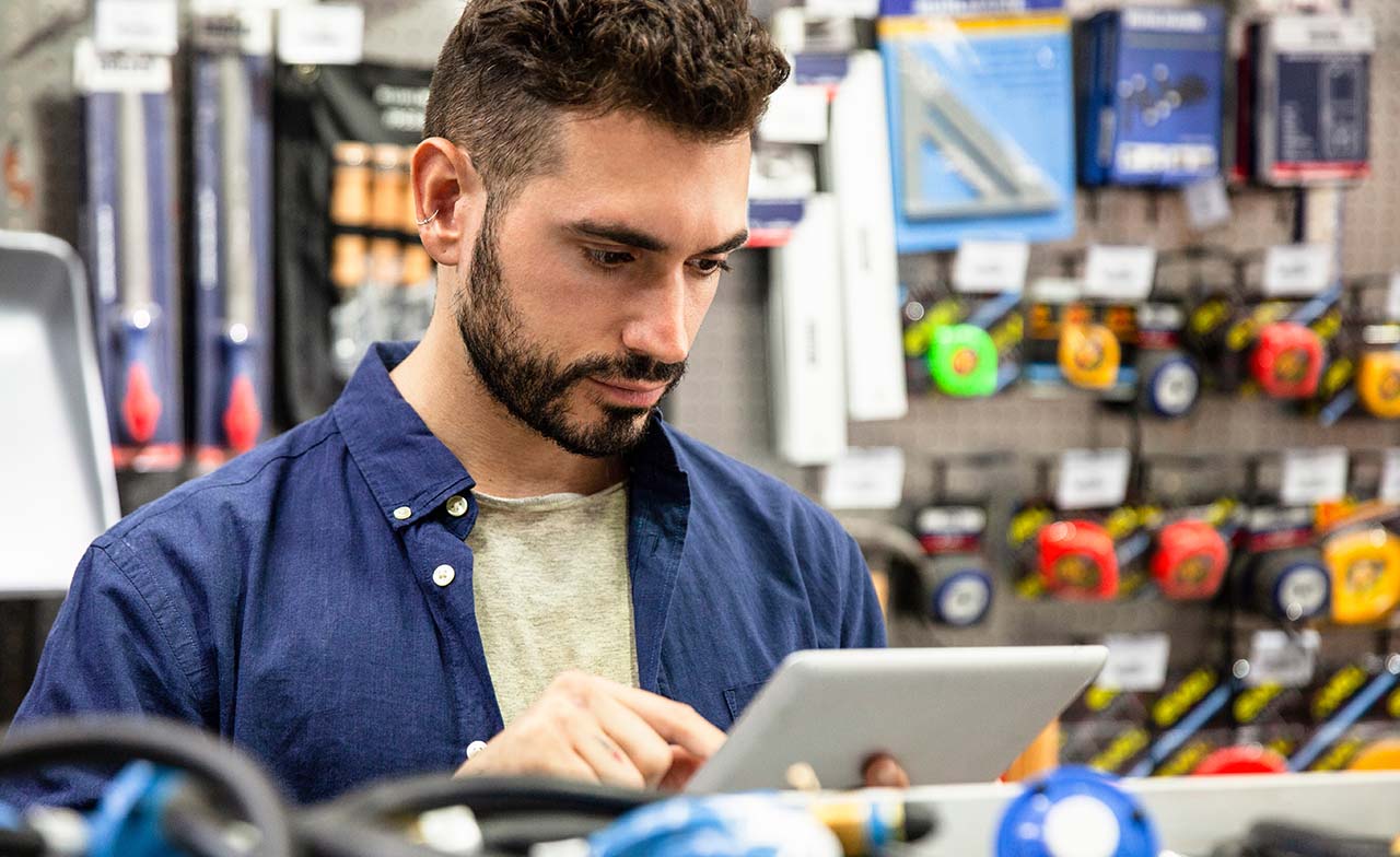 employé de quincaillerie travaillant sur une tablette numérique