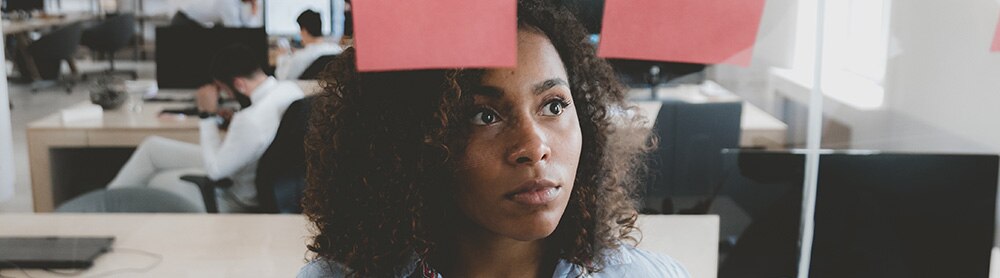 Young female employee looking onto a glass wall with sticky notes