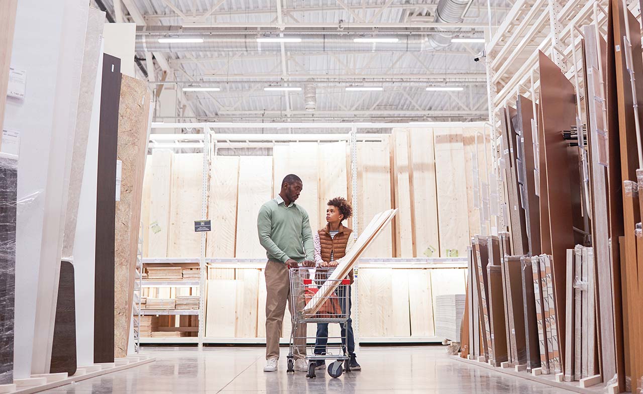 Father and son shop for home improvement in a wood aisle