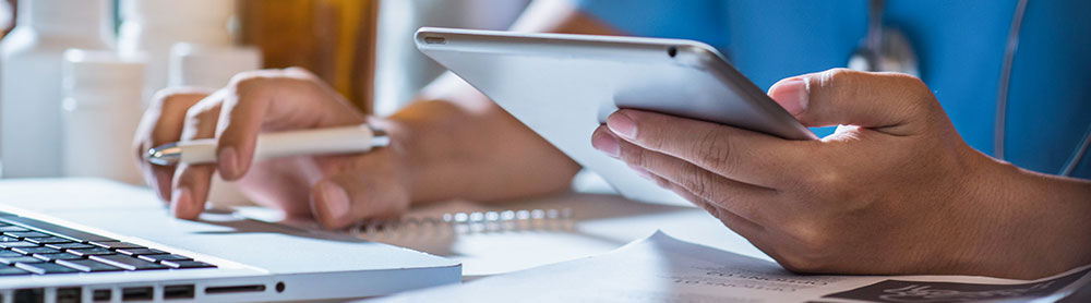 Close up of Doctor using a laptop and tablet device