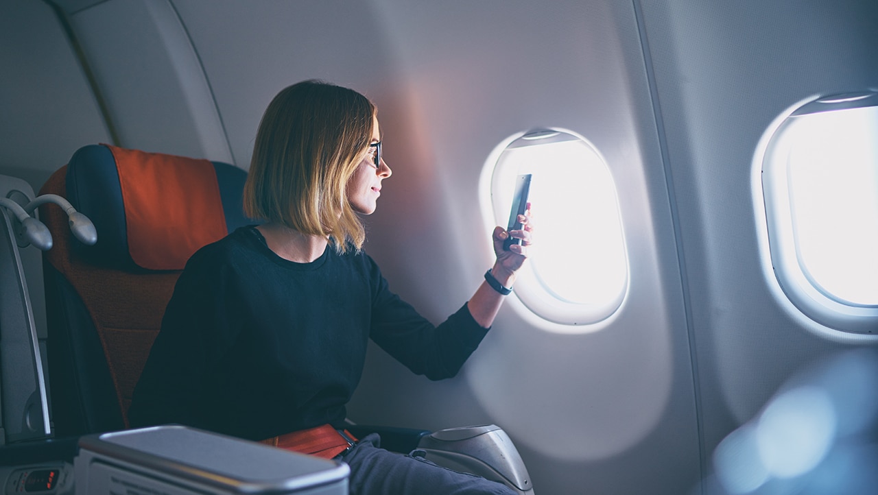 Reisende bruker mobiltelefon til betaling om bord på fly. Reisende bruker mobiltelefon til betaling om bord på fly.