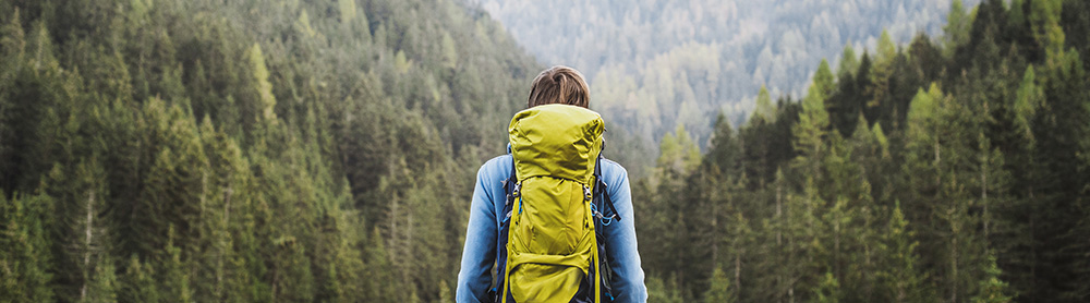 Une personne en randonné dans les montagnes portant un sac à dos.