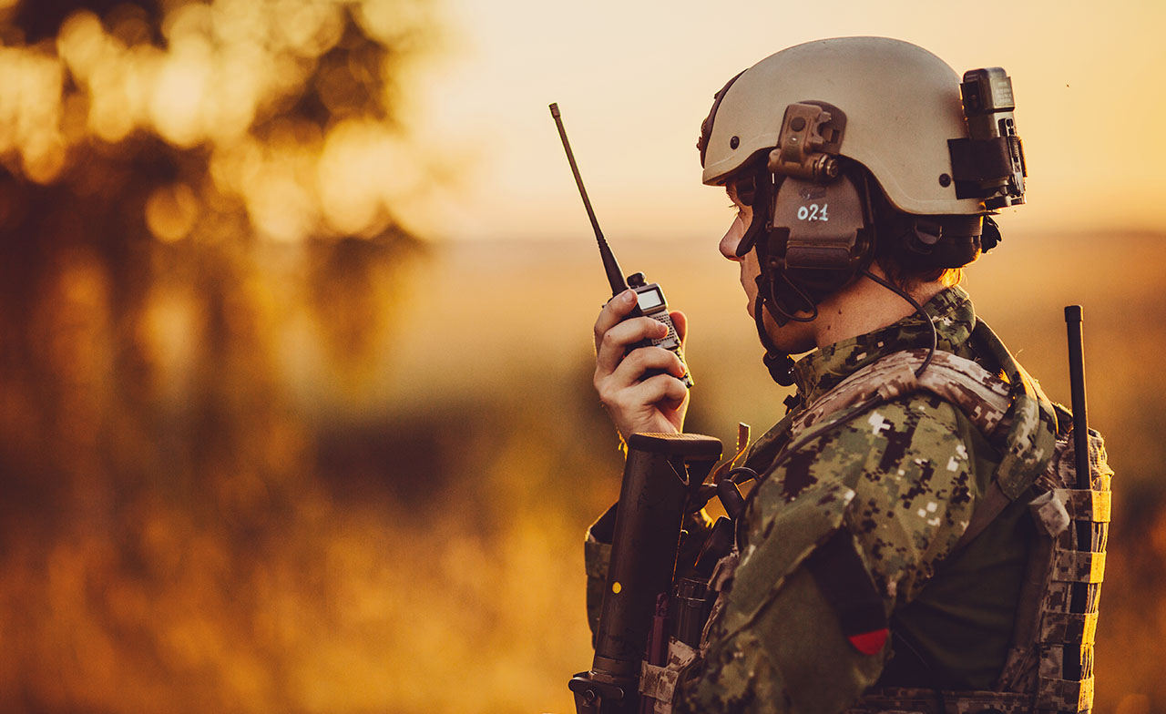 Soldat militaire parlant dans une radio de campagne avec un coucher de soleil en arrière-plan