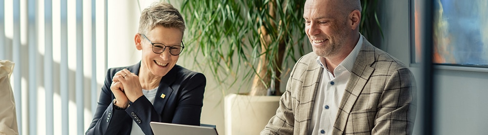a man and a woman smiling in front of a pc