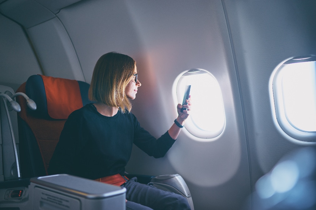 Business woman taking photo on smartphone while sitting in airplane