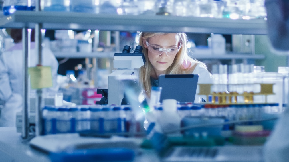 A woman wearing safety goggles works at a laboratory