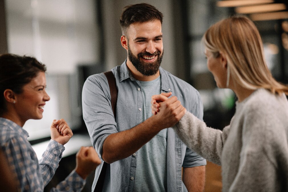 IIoT-Projektteam begrüßt sich mit einem Faustgruß im Büro.