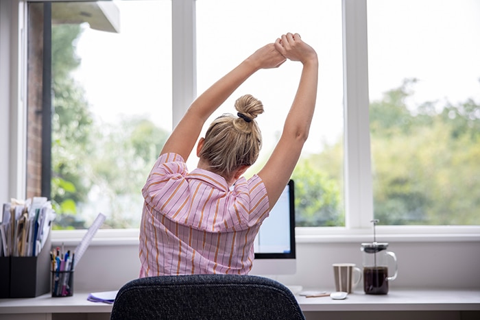 a woman stretching in front of her computer
