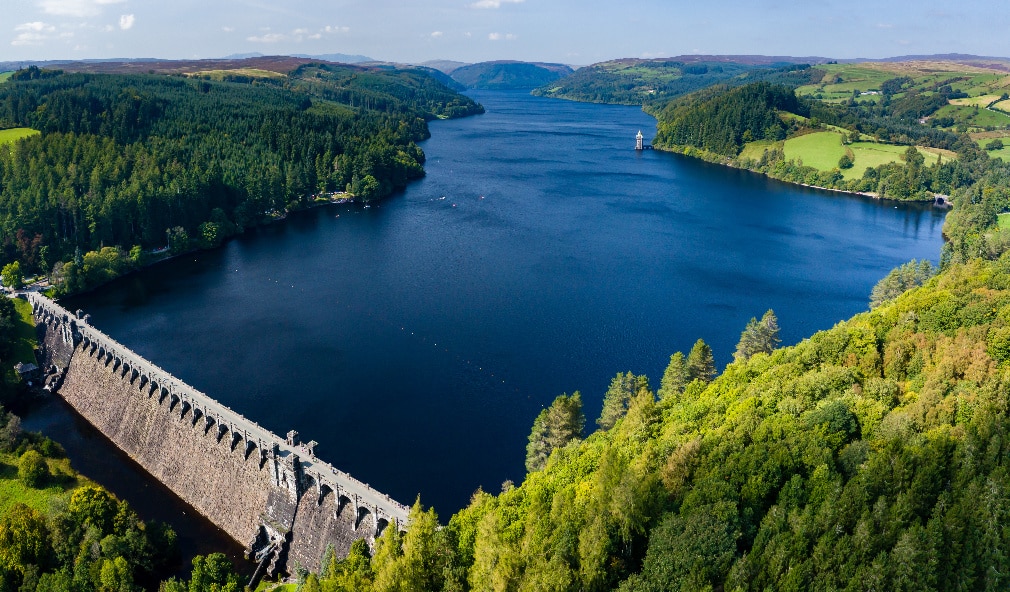 Aerial view of a large reservoir surrounded by forested hills and farmland