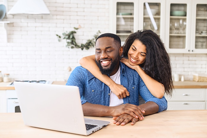Man and woman looking at computer screen in kitchen