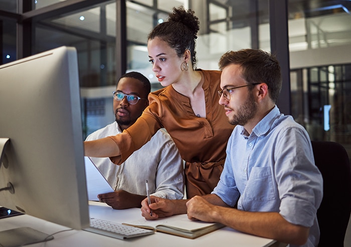 a group of professionals all looking at a computer together