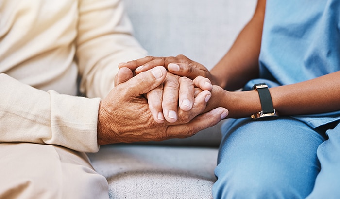 A healthcare worker and patient holding hands 