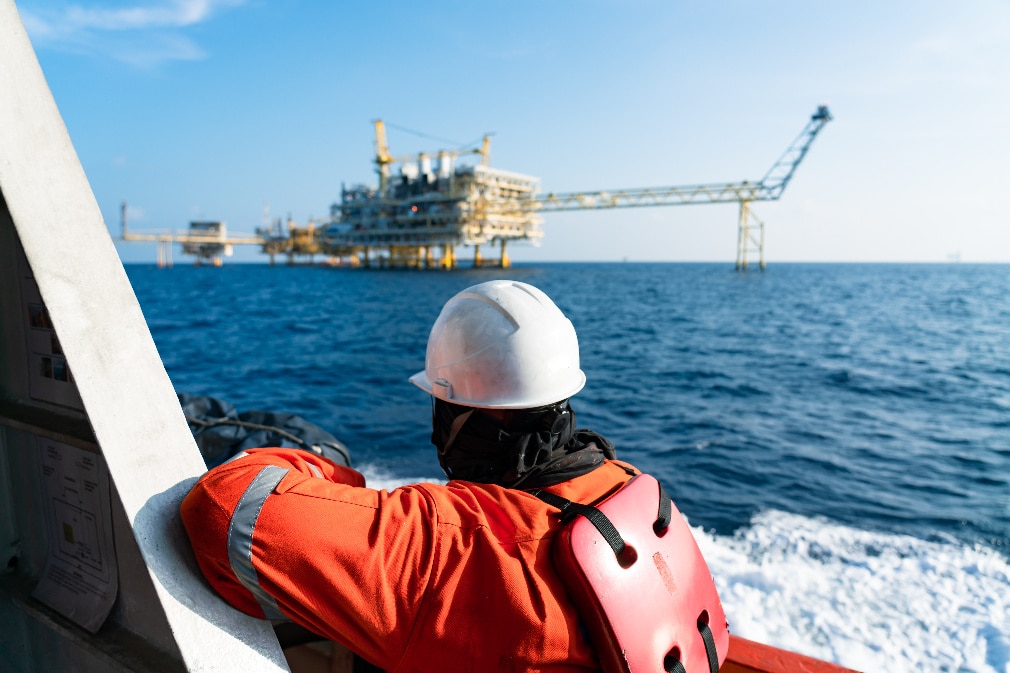 Man on a boat near an offshore oil and gas wellhead remote platform Man on a boat near an offshore oil and gas wellhead remote platform