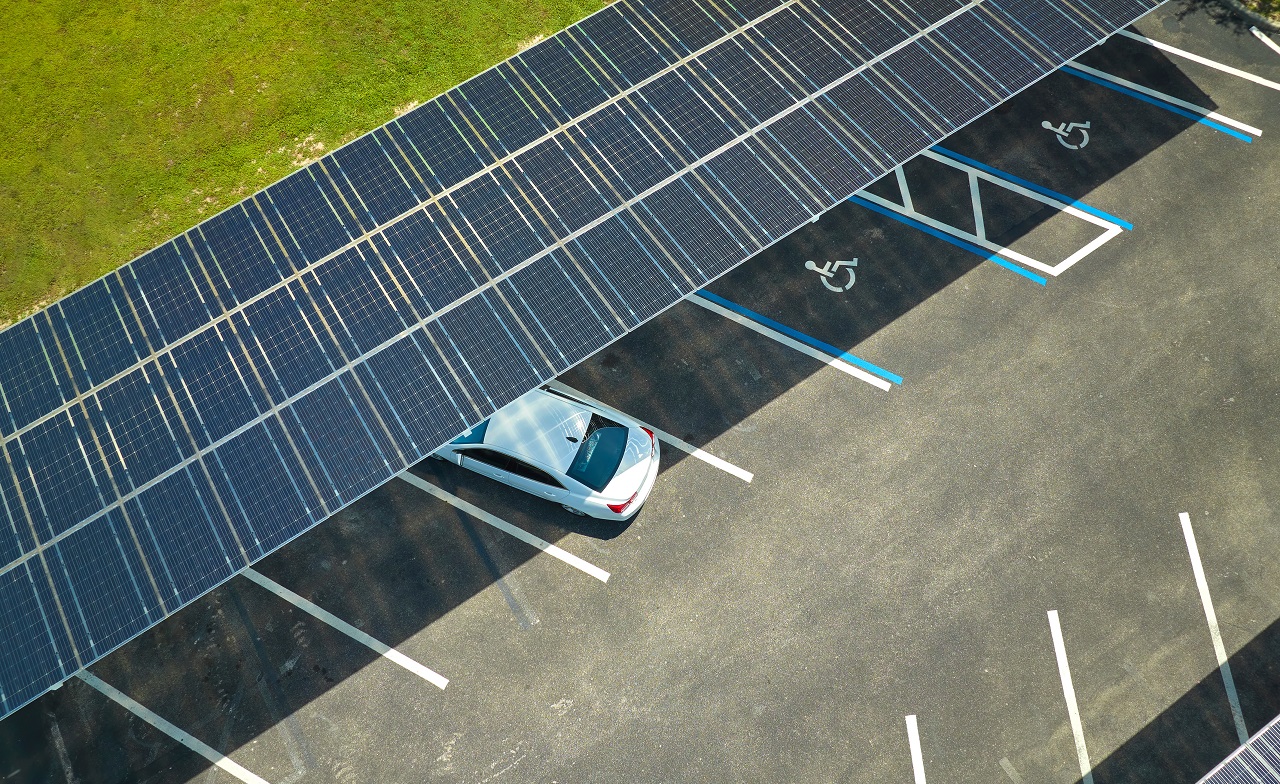 Luftaufnahme eines auf einem Parkplatz geparkten Autos mit Sonnenkollektorabdeckung