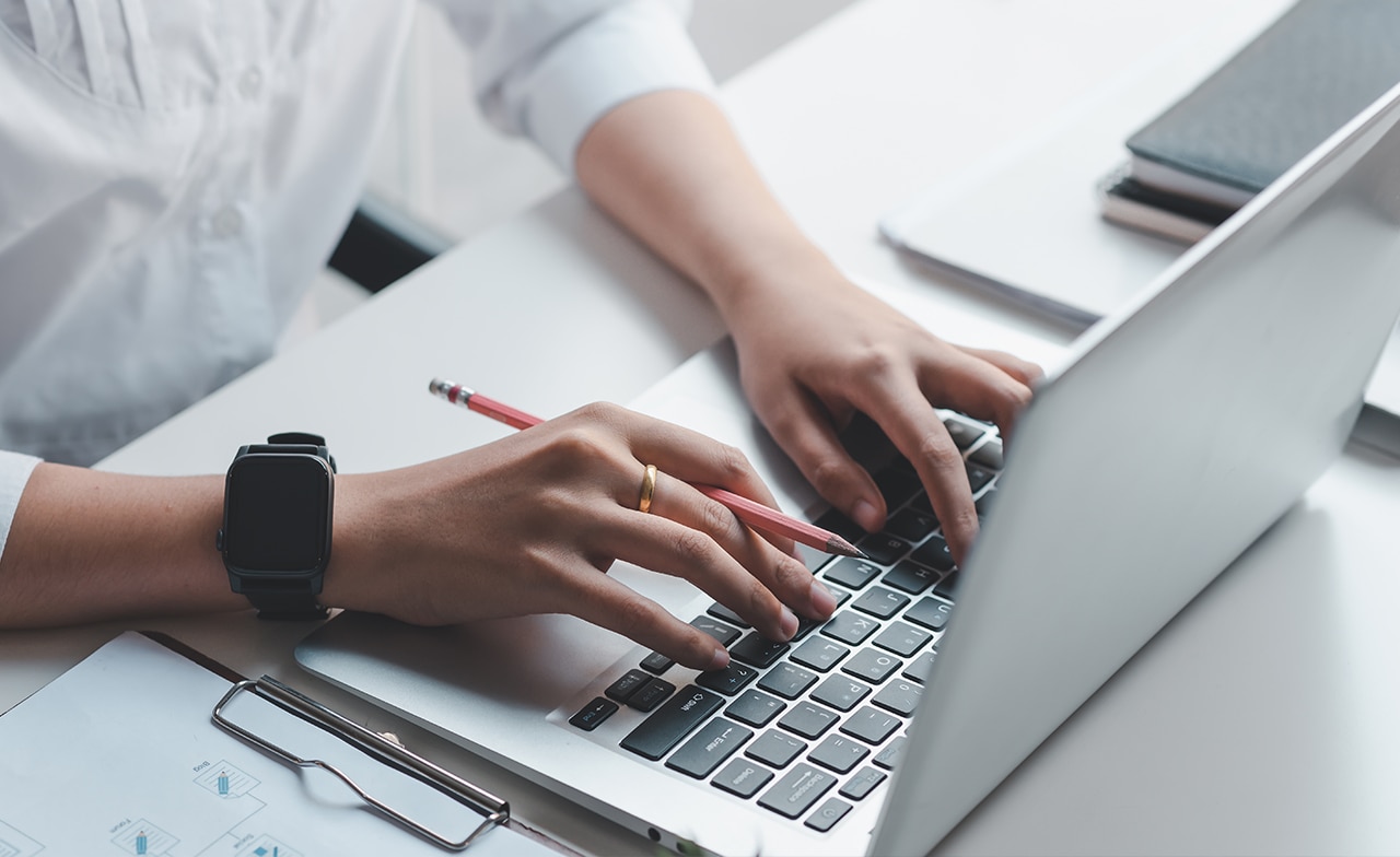 AFI_433098168 Hender skriver på bærbar PC ved ryddig skrivebord.