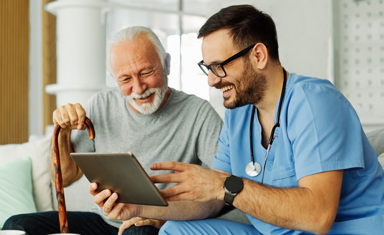 Care provider with an elderly patient looking at an Ipad 