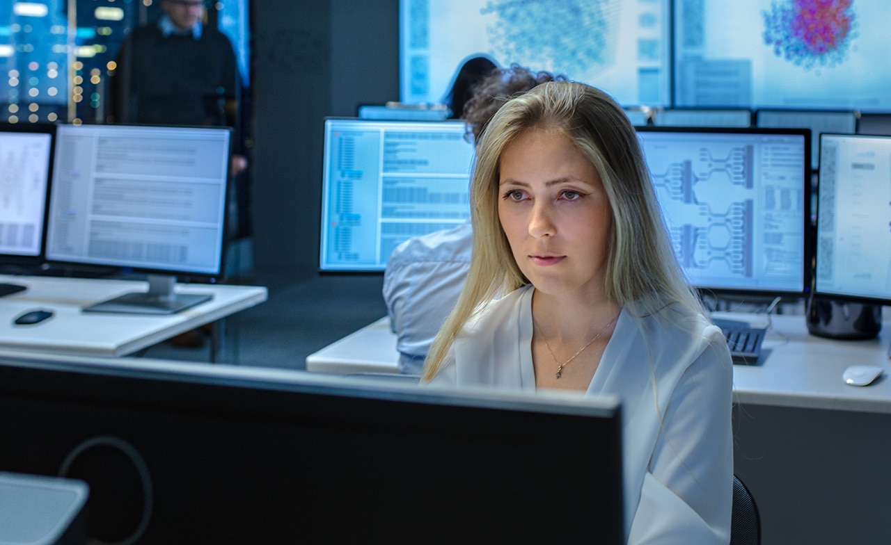 Kvinne foran skjerm i teknologimiljø