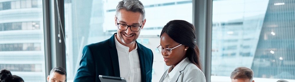 Two people standing talking and pointing at a tablet being held