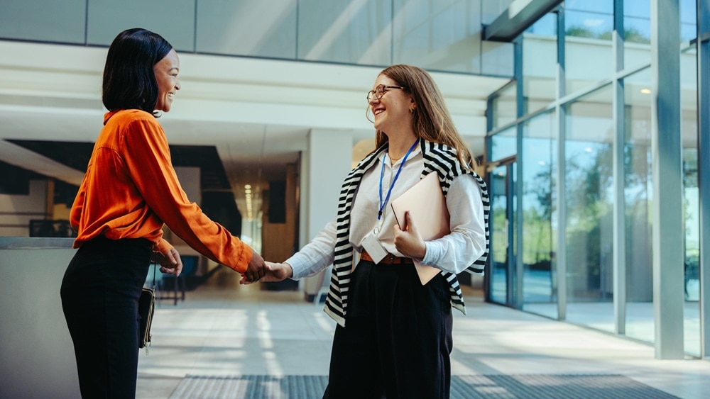 Business women shaking hands outside of a modern office building entrance