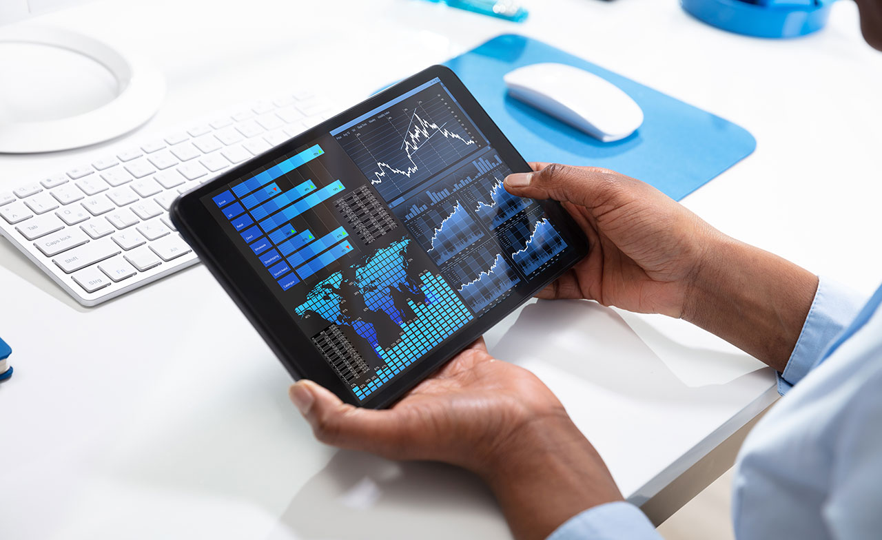 En person håller en surfplatta som visar ett digitalt analysverktyg med diagram, grafer och affärsdata. Bilden illustrerar dataanalys och digitalt beslutsstöd.