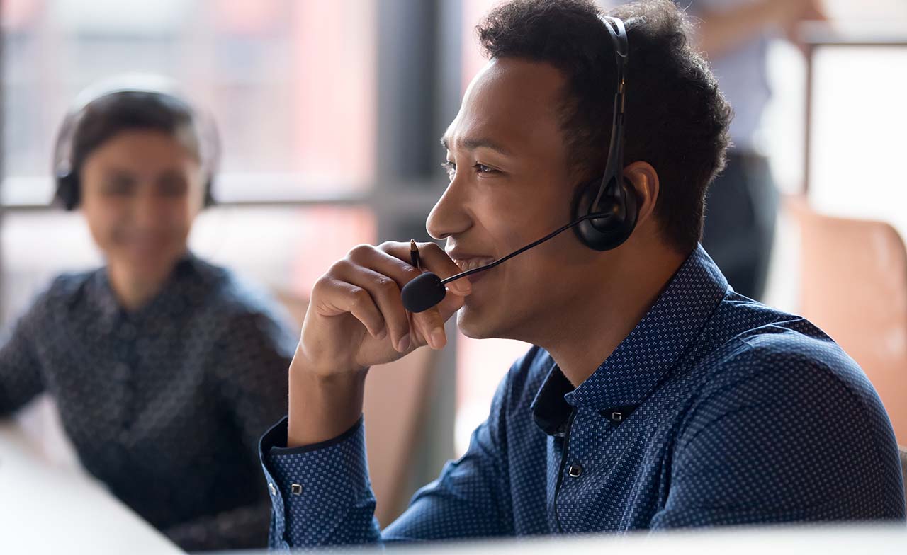 Mitarbeiter im Servicecenter mit Headset bei der Bearbeitung von Fahrgastanfragen im Conversational-AI-Projekt.