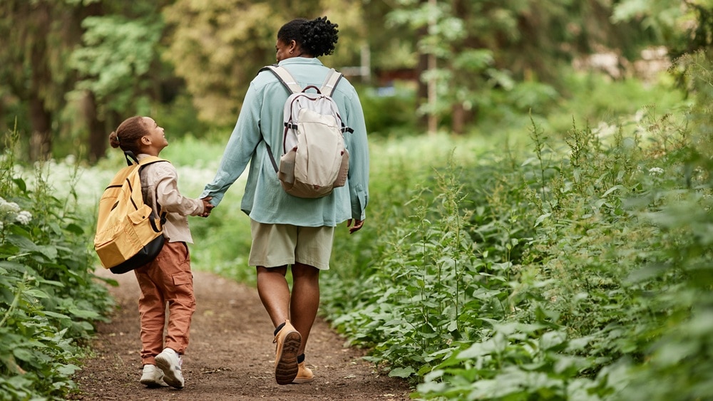 A child and caregiver walking down a forest path