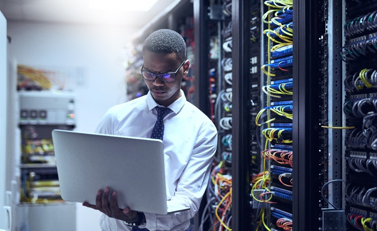 Cloud consultant on laptop in server room