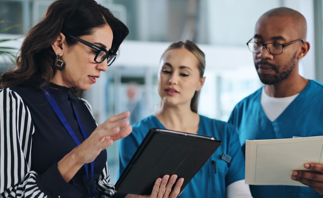 consultant discussing data on a tablet with healthcare professionals consultant discussing data on a tablet with healthcare professionals