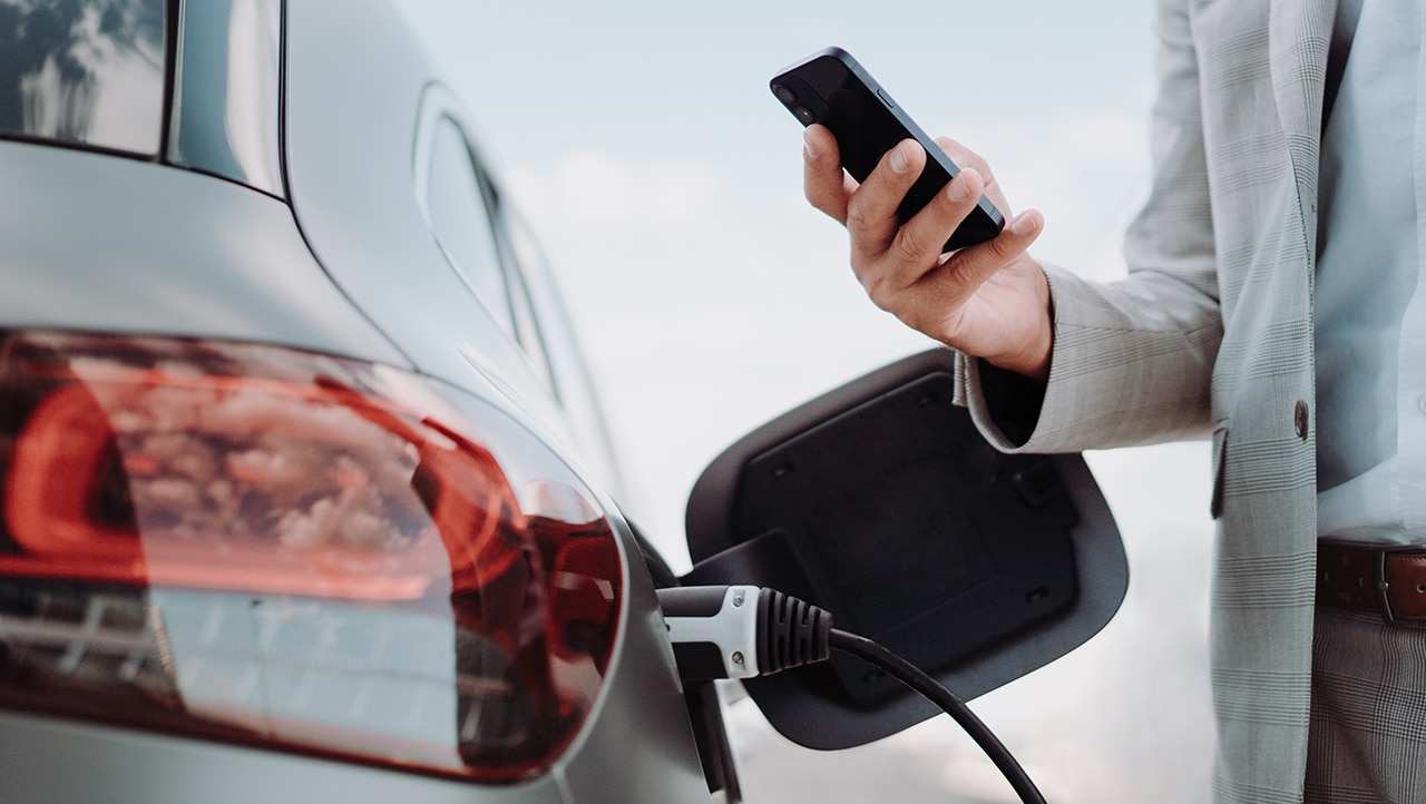 Kunde bruker mobiltelefon til betaling mens elbilen lades Kunde bruker mobiltelefon til betaling mens elbilen lades