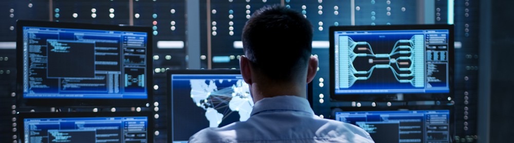 Cyber security consultant looks at multiple computer screens
