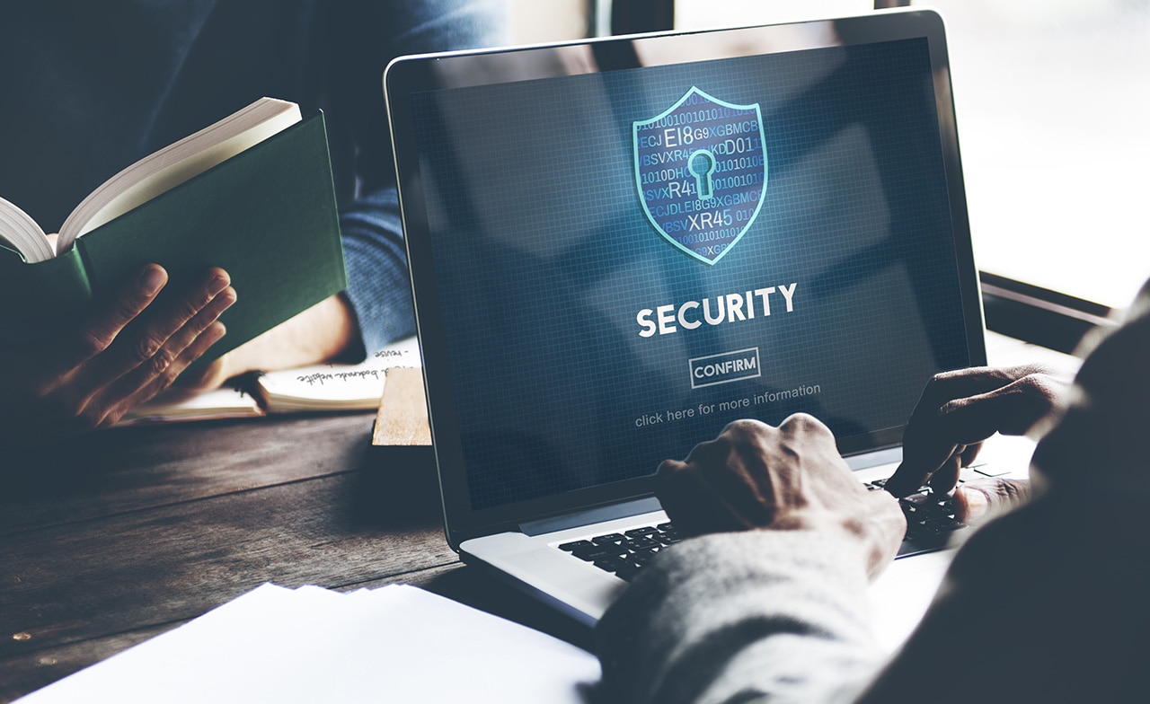 Person skriver på laptop med sikkerhetsskjerm og skjoldikon.