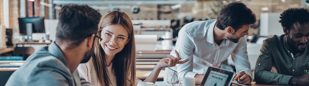 Four people in office discussing digital strategy at a meeting table