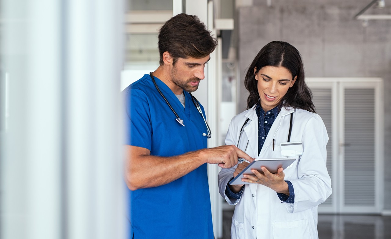 A doctor and nurse looking at a tablet in discussion