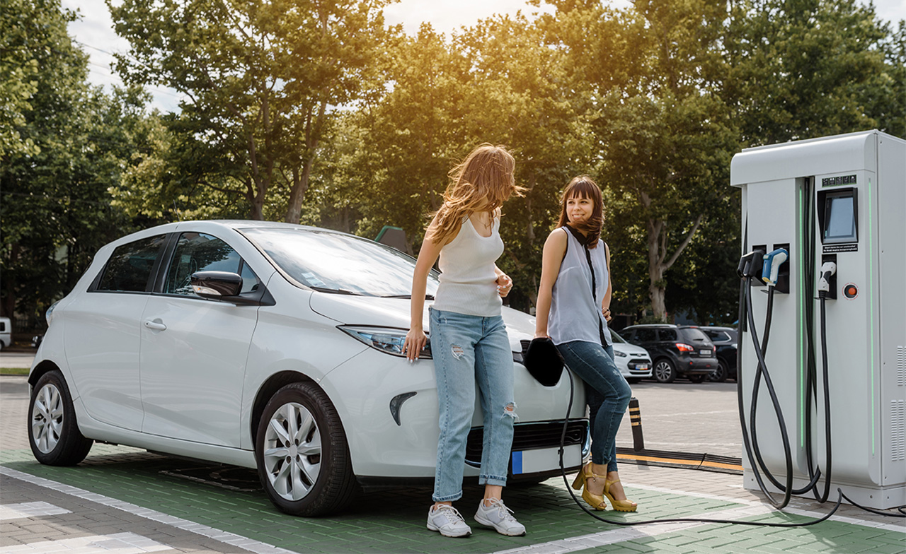 Two women waiting for an electric car to charge