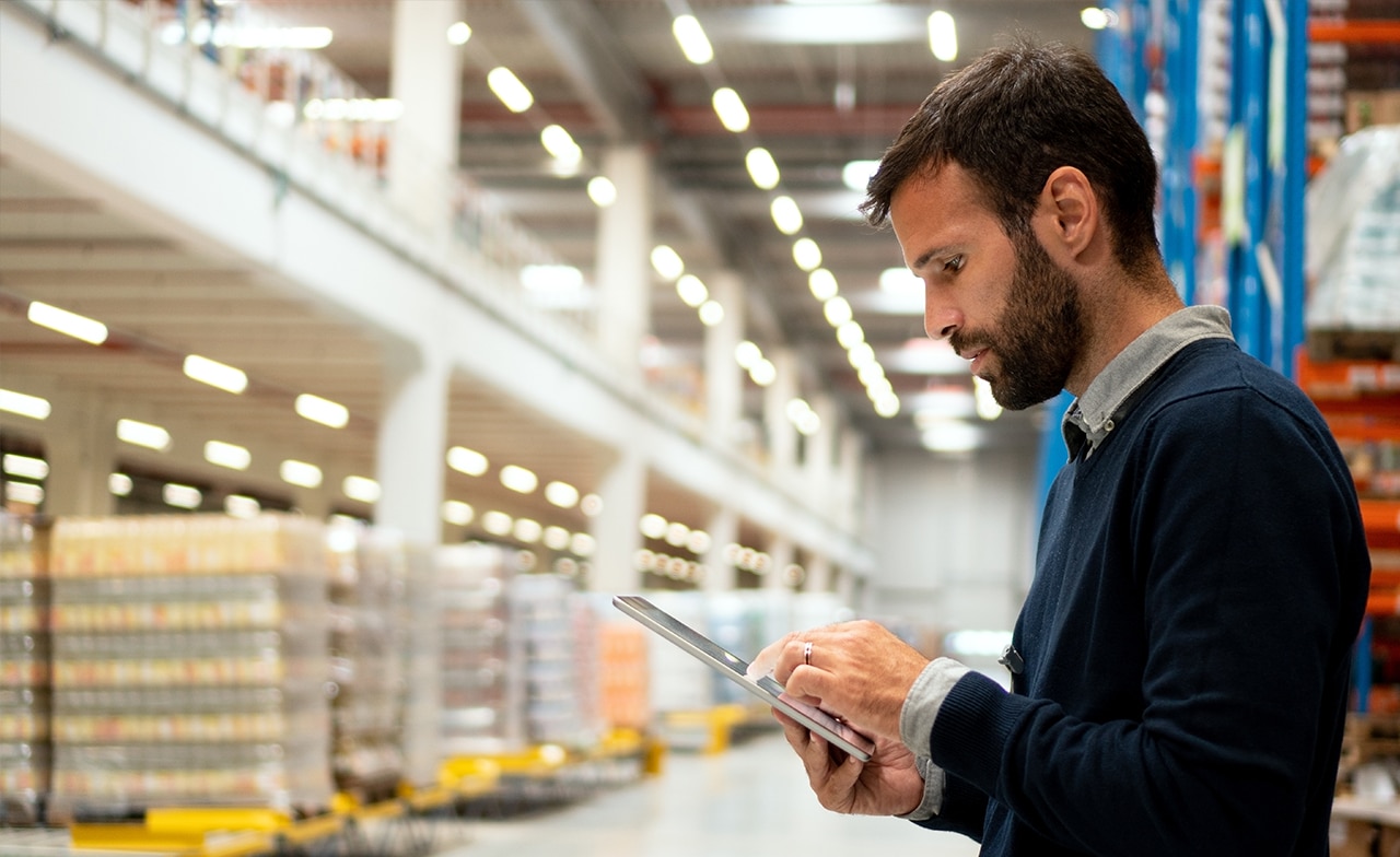 Mann bruker nettbrett i stor lagerhall