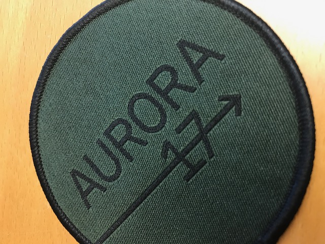 Närbild på en tyglogotyp med texten Aurora 17