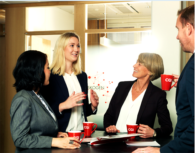 Tre kvinnor och en man från CGI står vid högt cafébord utanför konferensrum och pratar under en kaffepaus om Karriärbarometern