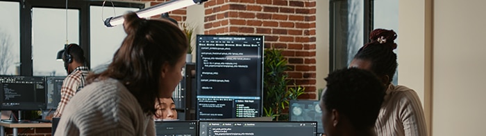 colleagues gathered around a computer looking a code on screen