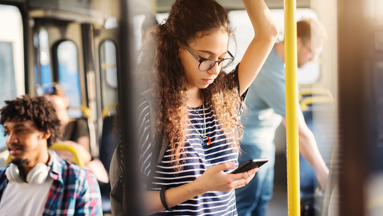 Nuori nainen matkustaa bussilla ja käyttää älypuhelinta