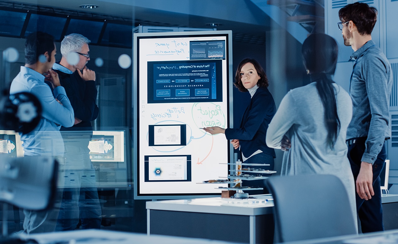 Group of professionals discuss data seen on a smart screen