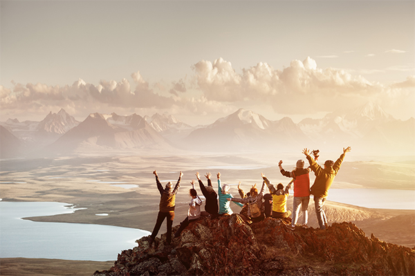 En grupp människor som står på ett berg med armarna i luften.