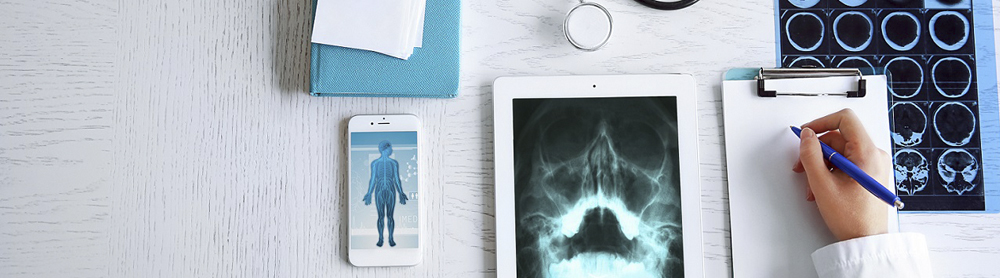 Arzt schreibt Patienteninformationen auf und nutzt Iphone und Tablet