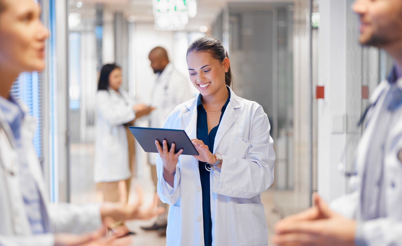 Eine weibliche Fachkraft in weißem Kittel, welche ein Tablet benutzt