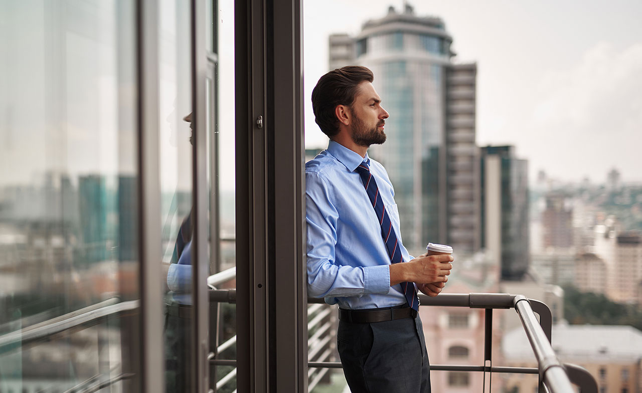 Person in business attire standing on a balcony overlooking the city
