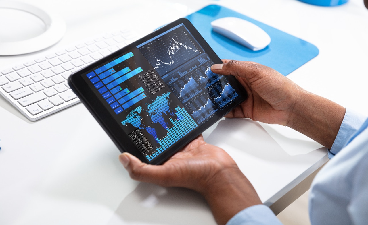 Hände, die ein Tablet-Gerät halten, das Diagramme anzeigt